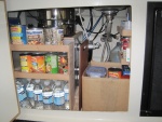 Storage under sink, the water heater is behind canned goods, cooking ware stored on water heater