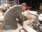 Shipwright Bob Tuckee working on the starboard/aft cover (lid) next to motor well and aft of cockpit seat/locker