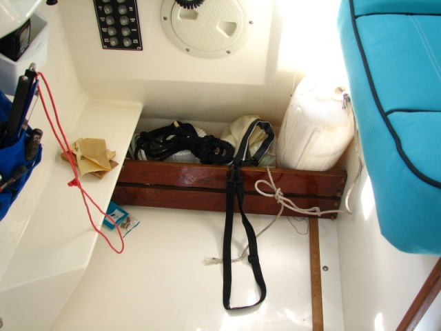 Corral for spotlights, fender, ditch bag on the floor outboard of helm seat