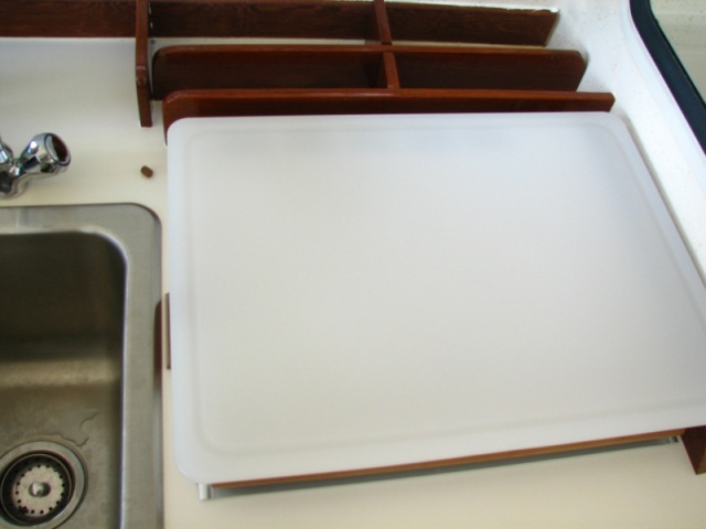 Divided space behind stove and cutting board which just fits over the stove--teak legs which will keep it in place 