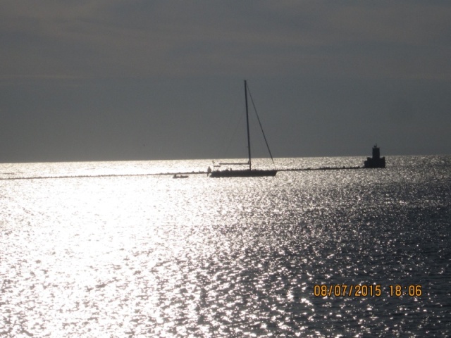 A sailboat with its tender anchored behind the breakwall.