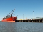 A ship loading something.  Bet is has something to do with wood.