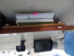 Overhead shelf, this side for storage of charts and cruising guides the other side for manuals.  There is velcro attached teak fiddle to prevent loss of items.  Monitor is for rear view camera.