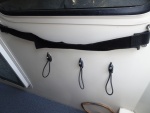 strap on top holds folding chairs in place.  Bungee cord holders for dock and extra docking lines.  One from bow, one from amidships cleat and one extra line.  Also in aft cockpit is a single similar bungee attachment for each stern line