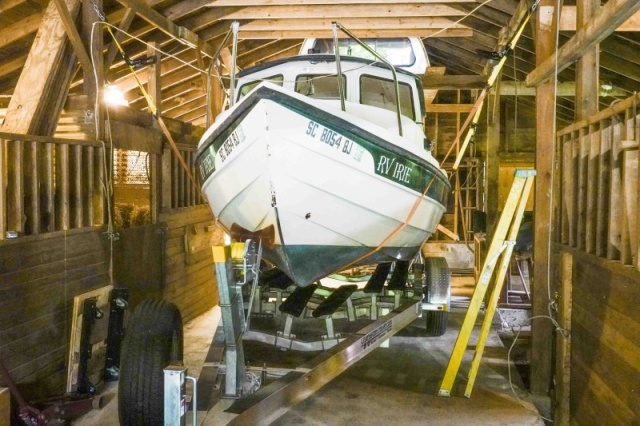 The floor jack was used to lift the stern, then a tow strap was put under the stern with each end of the tow strap attached to a ratchet strap suspended with chain from the ceiling. Then the same was done to the bow. Now the trailer can be pulled out form under the boat.
Although the floor jack was used to do the lifting, I discovered that I can lift or lower the boat simply by using the ratchet handles alone.