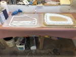 First I made the lid bases. At right of photo I've assembled the four mold parts for the lid base for the starboard locker. On left of photo are strips of 1708 ready to wet out and lay in the mold.