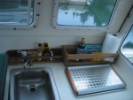 (CheckRaise) A galley storage solution. The teak rail and standalone shelf unit are simply velcroed in.
