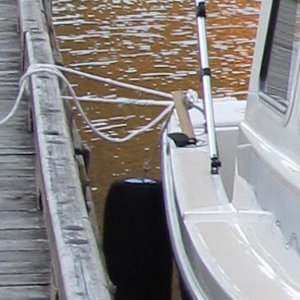 Not the best photo - I'll try to get a better one in future.  This is an alternative method of hanging the after fender.  I got the idea from Will-C and wanted to try it since the fender hanging from the after cleat can tend to get aft of the boat.  The basic idea is to put some sort of dowel into the rod holder (these were already in my boat) and then hang the fender from it.  I started with Schedule 80 PVC pipe (1" IIRC), but didn't really like handling it, so this is an ash tool handle replacement (bought at Ace Hardware).  To secure the fender whip to the dowel, I drilled a hole through the dowel, and then run the whip through it and then tie a figure-8 knot.  That way it is adjustable if necessary.  I left the dowel this long because it then keeps the whip/line off the gelcoat at the edge of the deck.