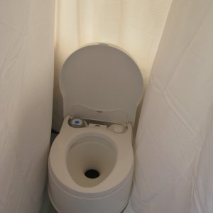 01 Marinaut 215 cockpit temporary portable toilet enclosure.  This enclosure is very private, and because the sides are flexible can easily expand out to about 3 feet wide.  (In this picture, the enclosure falsely appears to be only 18 inches wide because the wind, blowing into the cockpit from the right is pushing the curtain in toward the stern.)