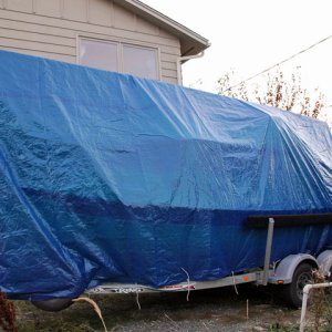Port view of tarp tied to the frame of the trailer with bungee cords and lines.