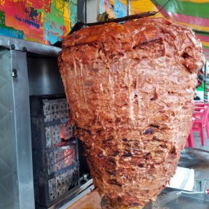 Thin layers of marinated pork stacked on a spit then slowly rotated in front of the flames, then thinly sliced off for \"al Pastor\" street tacos, so good!