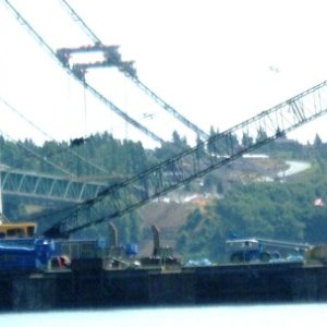 Bad photo, sorry. Barge that will move road deck piece under gantry cranes. Notice huge blue 750 hp thruster motors that will help keep the barge in place using a GPS system. A tug will also be used. 
The thrusters are shown here in the up position.