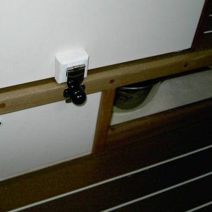 The hasp in the closed position locking the seat in the aft position. Area under seat to left is the storage compartment under the table.