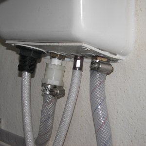 Media 'Long nylon fitting kept pulling off center, causing leak. Finally just heated the hose and clamped it directly to the shower hot faucet input threads. The back, left shows the original nylon fitting on the cold faucet. The back, right shows the hose clamped directly on the hot water faucet threads. No leak now!' in album 'Aft wall of the under sink cabinet showing the hot water faucet "fix" by just tossing the nylon fitting and clamping directly to the faucet threads after heating the hose.'
