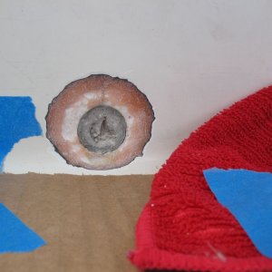 A perfectly circular crack in the the center (athwartships) of the splashwell gelcoat  turned out to be a "phantom" drain that had been drilled for but then simply filled and gelcoated over, presumably at the builder or dealers.  Subsequent conversation supplied me with the info that the center location was typically used for twins (my boat has two engines, but not twins).  This type of "repair" (just filler and gelcoat) is destined to crack, which it had.  I ground it back in a taper to prepare for adding fiberglass cloth.  Actually here I had taken away too much of the fiberglass (pink bits) and so ultimately I increased the diameter and improved the taper (leaving more glass to bond to), but I don't have a photo of that.  This gives the idea, anyway.