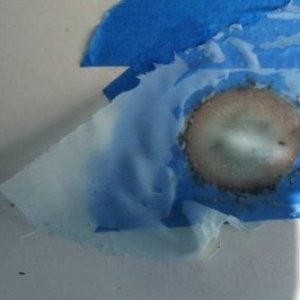 Here I have fiberglassed over the depression.  I started with neat resin, then leveled the center with thickened epoxy (colloidial silica), and then added concentric layers of 10 oz. cloth.  I added some peel ply (release cloth) over the top to smooth it - that's the "windbreakery" looking stuff you can see.  You can see the "real" drain over to the left in the photo.