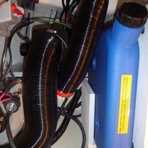 Media 'SMALLER BLACK HOSE TO THE RIGHT OF RED TAPE COMBUSTION AIR INTAKE, INSTALLED SAFETY POWER CUTOFF SWITCH SEE RED LEVER FOR OFF AND ON ABOVE LEFT SIDE OF THE PICTURE' in album 'Basic mounting under the helm seat where refridgerator was removed. Fresh air intake under right side of seat box just beyond the heater on the left from this view. Heat exhaust under foot box in the helm seat area. Mount made out of 1/4 inch aluminum and 3x4 aluminum angle bolted to front of helm seat box. The four bolts up top are the existing four bolts for the helm seat. I used them for securing the extra long wires from my outboard motor controls and on off switch, bolted fuse holders etc, the heater sits right under the helm seat. What's different also is the hot air exhaust has been changed to 3" instead of the normal two inch, as I will add a Y pipe for a second duct if need be. From what I noticed so far a second duct won't be needed. This heater puts out better than an ugly girl on prom night.'
