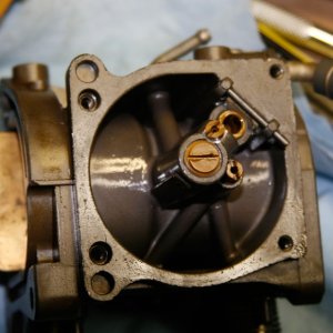 Carb-viewed-from-bottom-with bowl-cover-removed: Below brass cap screw in center lies main nozzle and emulsifier tube (slow jet). Two other jets unscrew for inspection and cleaning. Float has been removed.