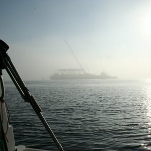 Fog lifts to reveal barge with deck section ready to lift