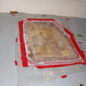 Here is the new core with two layers of glass cloth and Peel Ply release fabric over the whole repair.  Peel Ply allowed me to fair out the resin.  The surrounding exploratory holes and the bored out old pop rivet holes have all been filled with epoxy putty.  The mess is cleaned up.