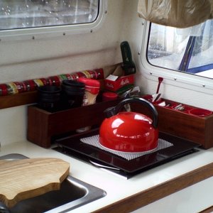Galley area.  2 lift-out boxes made from 50 YO mahogany.  Back box holds coffee cups, etc.  Side box has small cups from Chuck E. Cheese which holds condiment packets form various fast food outlets.