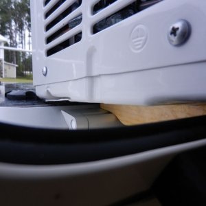 The backs of the "feet" are cut so that they sit on the hinges of the hatch.  They are cut down so that they cause the AC to angle back for good water drainage.  They are just high enough, though, to keep the AC off of the lexan.