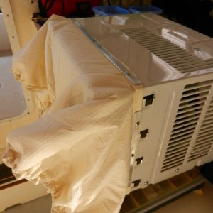 Lisa made the sock to have the exact rectangular opening of the AC unit on one end,, and  the measured outer window frame on the outer edge.  

I used thin aluminum strips and VERY short sheet metal screws to fasten the "sock" to the AC unit.  The outer edge has 1/4" bungee cord in a hem and one of those squeeze cinch thingies.

There is two fabric layers with some insulating foam in between them to help (marginally) prevent air-to-air exchange.