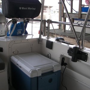 View of 12V Fridge, double 12V outlets, cup holder, 4 inch cleat on side of baitwell to strap cooler in place in rough water or on highway, Magma Newport grill which holds all the accessories inside, and gas cylinder holder bag.