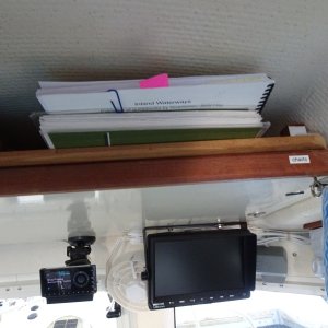 Overhead shelf, this side for storage of charts and cruising guides the other side for manuals.  There is velcro attached teak fiddle to prevent loss of items.  Monitor is for rear view camera.