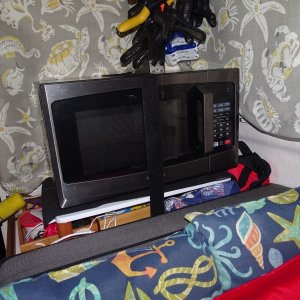 Microwave on shelf--raiser has small boxes with often needed items under--first aid kits are outboard.  Clips for the sun shades on the cockpit sides are above