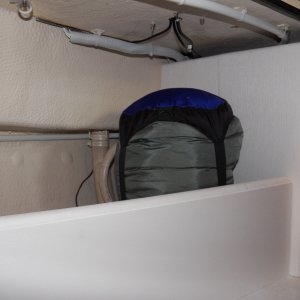 Media 'Sleeping bag in the cubby.  I'm planning on using the flat panel to mount my flare gun kit and a second fire extinguisher.  The "exposed" wiring that is left is mostly in white conduit and would now be very difficult to snag.' in album 'All of the electrical wiring just hangs loose on the back of the helm, which is in the V berth on the 16.  I've still got a few more modifications (like a negative buss bar) and then I need to cover it up.'