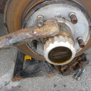 A long bar or steal rode works great to secure the wheel while removing cap.  Next time I will loosen the caps before removing the wheel, da!