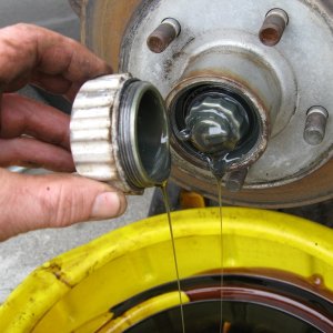 Twist off cap and let drain. Remove cotter pin and bolt, hub will now slide off. Remove front bearing and washer.