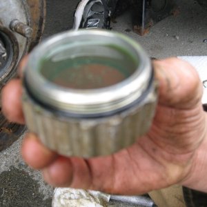 This really works, fill-er-up.

Fill the oil cap completely full with gear oil than twist it on.  Even if you don?t catch the thread perfectly and have to back twist you probable will not lose more than a drop or two.  Believe me this is a lot easier than trying to fill the hub through the little hole in top.  A full cap will top it off perfectly, its how they do it at the factory.
