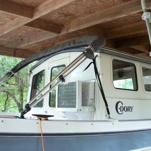 Exterior view of AC. Exterior panel above AC is cut to the same size as the original window and painted white. A cover for the AC will be made in the future. View of the shelter, constructed for a previously owned pontoon boat did not allow enough overhead clearance to consider a roof top AC.