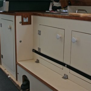Galley cabinets were cut into the starboard seat box. Hinged lid covers long box used to hold rope, tools and other stuff. The whale foot pump works great and conserves water. At left of top center is a clip that mates with fingers on the starboard bed support.
