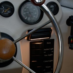 Media 'Flip light provides directed light onto the control switch panel. Very useful at dusk when you can't see the panel but do not want bright lights while your eyes adjust to the dark.' in album 'Copilot storage made from lucite sheet cut, heated and formed into a simple L shape. Mounted to forward bulkhead and seat box. Teak trim stiffens and covers the top edge.'
