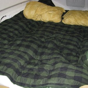 Media 'Fully extended berth showing head-first sleeping arrangement. Shown are two, queen size pillows.   We bought two flannel sleeping bags, good to 40 degrees, for $136 at LL Bean.  We unzipped them, using one for the bottom, which sat on top of our fiberbed topper, and the other was used as a comforter.  Overall, this sleep space is roughly 6 feet long by 5 feet wide, with a slight decrease to 4.5 feet at the bulkhead.  We slept better is this berth then we did at home.  9/26/12 comment.  This berth is a lot larger than one would think.  I can sleep across the bunker once past the bulkhead.  The only issue with sleeping toward the bow is the deck is close to one's head, but that's OK after awhile, since you have a cavernous view of the cabin from that perspective as well as having the hatch overhead.  Another thing that should be considered is that if any of you suffer from heartburn like I do, you know that it is infinitely preferable for your head to be higher then your feet.  Sleeping with your head toward the bow achieves this.' in album 'Fully extended berth showing head-first sleeping arrangement. Shown are two, queen size pillows.   We bought two flannel sleeping bags, good to 40 degrees, for $136 at LL Bean.  We unzipped them, using one for the bottom, which sat on top of our fiberbed topper, and the other was used as a comforter.  Overall, this sleep space is roughly 6 feet long by 5 feet wide, with a slight decrease to 4.5 feet at the bulkhead.  We slept better is this berth then we did at home.  9/26/12 comment.  This berth is a lot larger than one would think.  I can sleep across the bunker once past the bulkhead.  The only issue with sleeping toward the bow is the deck is close to one's head, but that's OK after awhile, since you have a cavernous view of the cabin from that perspective as well as having the hatch overhead.  Another thing that should be considered is that if any of you suffer from heartburn like I do, you know that it is infinitely preferable for your head to be higher then your feet.  Sleeping with your head toward the bow achieves this.'