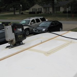 Masking tape to prevent splintering and wood strip attached to hold cut roof piece in place