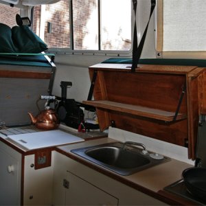 Galley from cabin door. Sunbrella pocket snapped to back of helm seat holds kitchen untensils, cups, plates and other stuff. Helm seat can be hinged up to give access to substantilly more counter space covered with ceramic tile for hot items.