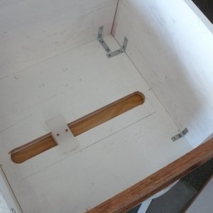 The Plastic "T" (made from cutting board) bolts down to/thru the floor. This keeps the seat box attached to the boat. Slide bolts hold the box in position, forward/aft side to side. A wood tray/cap goes over the "T", so it does not get in the way of gear storage. Or, if there is a drawer, the drawer will glide over the it. This system workes really well and is very simple to build.