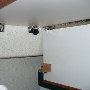 A hole was drilled thru the "L" bracket and a bolt with knob is used to hold things in place. This single bolt is really just a pin and is held in place by Velcro. It keeps everything in place very snug when the table is up folded down as pictured.