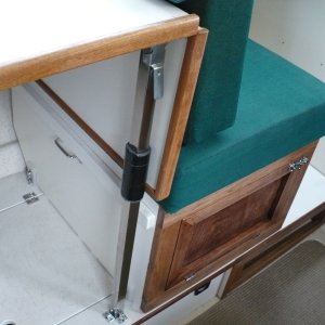 Media 'Note: The storage hatch cover Hinge was moved to the left so the box can slide back and a tab was added inside the hatch to support the lid. Also, I used some left over latch parts on the floor, this keeps the table leg from sliding backward. Also added a pad on the leg for the table to rest against.' in album 'Sliding seat in new position. 

A lumbar pillow is nice to use here. We often sit on a PFD cushion for a better look-out/view. Not pictured here, I added a snap under the table and a small strap snaps into it and then snaps onto the existing cushion snap. This hold the back-rest cushion in place.'