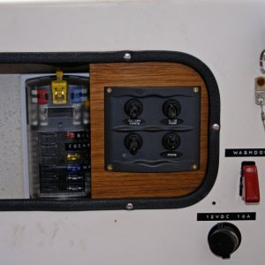 Switch Panel mounted on teak includes switches for port and starboard LED lights, additional Rule 1100 bilge pump plus one spare. Covered fuse panel to left is accessible and labeled.