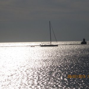 A sailboat with its tender anchored behind the breakwall.