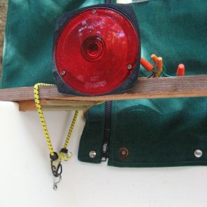 Trailer lights secured above splashwell with bungees; wiring routed through camperback and along port side to bow.