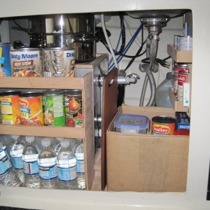 Storage under sink, the water heater is behind canned goods, cooking ware stored on water heater