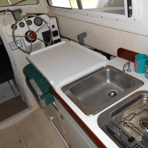 Tray lays over folded helm seat.  Also added OB battery charger under stove and against rear bulkhead.  Added inverter next to helm seat.. 120v plug behind helm seat fed by GFI plug next to charger.