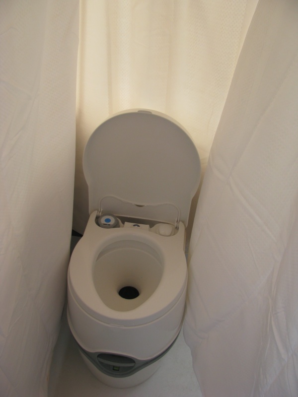 01 Marinaut 215 cockpit temporary portable toilet enclosure.  This enclosure is very private, and because the sides are flexible can easily expand out to about 3 feet wide.  (In this picture, the enclosure falsely appears to be only 18 inches wide because the wind, blowing into the cockpit from the right is pushing the curtain in toward the stern.)