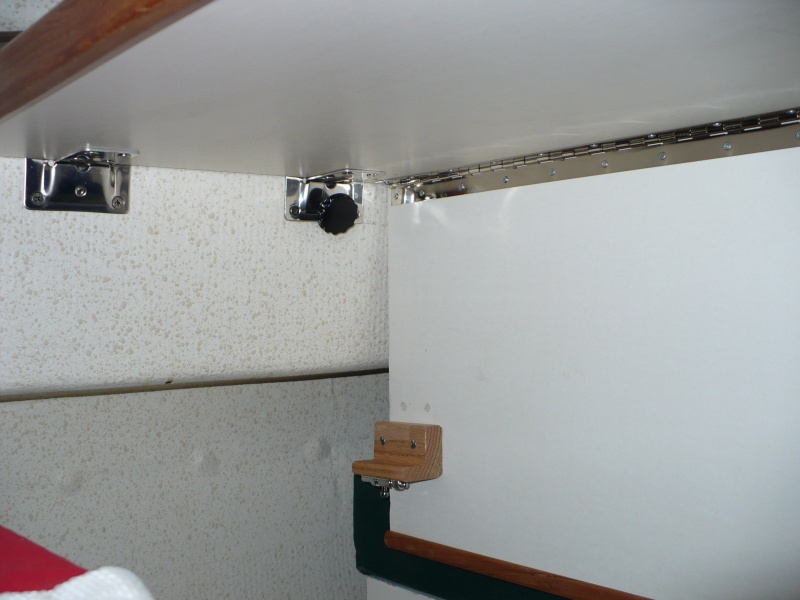 A hole was drilled thru the "L" bracket and a bolt with knob is used to hold things in place. This single bolt is really just a pin and is held in place by Velcro. It keeps everything in place very snug when the table is up folded down as pictured.